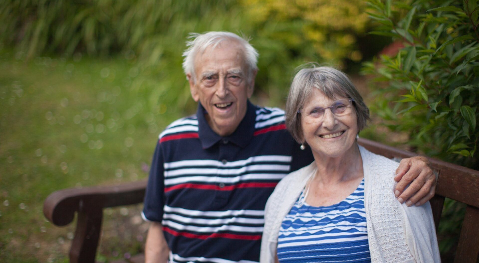 Older couple sitting on a bench in the garden at Revitalise Netley Waterside House