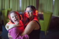 Revitalise volunteer and guest enjoying silent disco at the centre with glowing headphones on