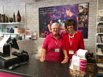 Two female volunteers behind the counter at the Revitalise Fair Oak charity shop