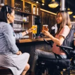A female who uses a wheelchair enjoying a drink with a female friend in a local pub