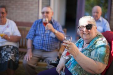 Female guest raising glass of wine in toast while sitting outside at Jubilee Lodge