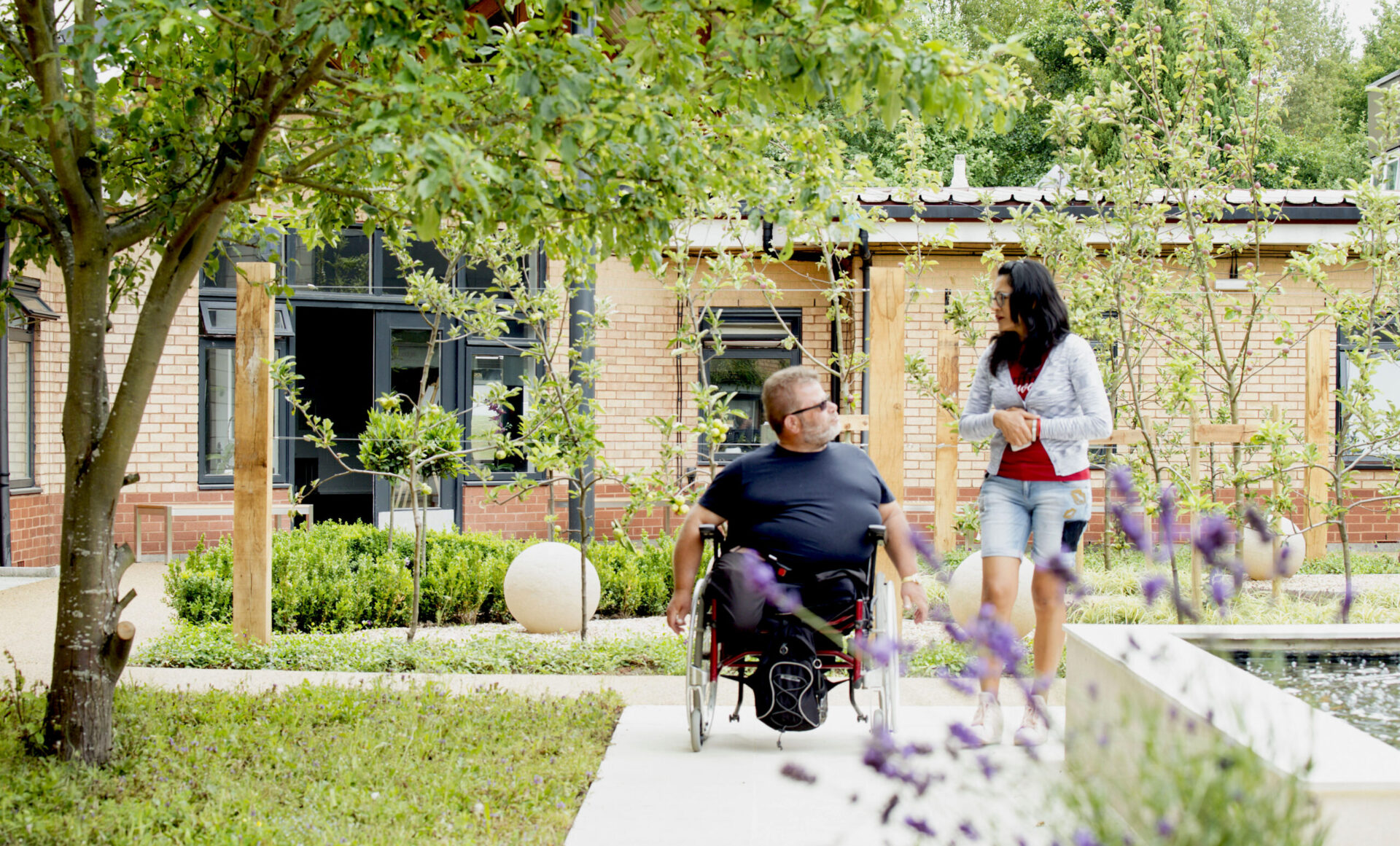 Man in wheelchair and woman talking in a garden