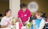 Care Assistant serving guest at Revitalise Jubilee Lodge