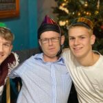 Two young men sitting with an older disabled man during Christmas time at Revitalise Sandpipers