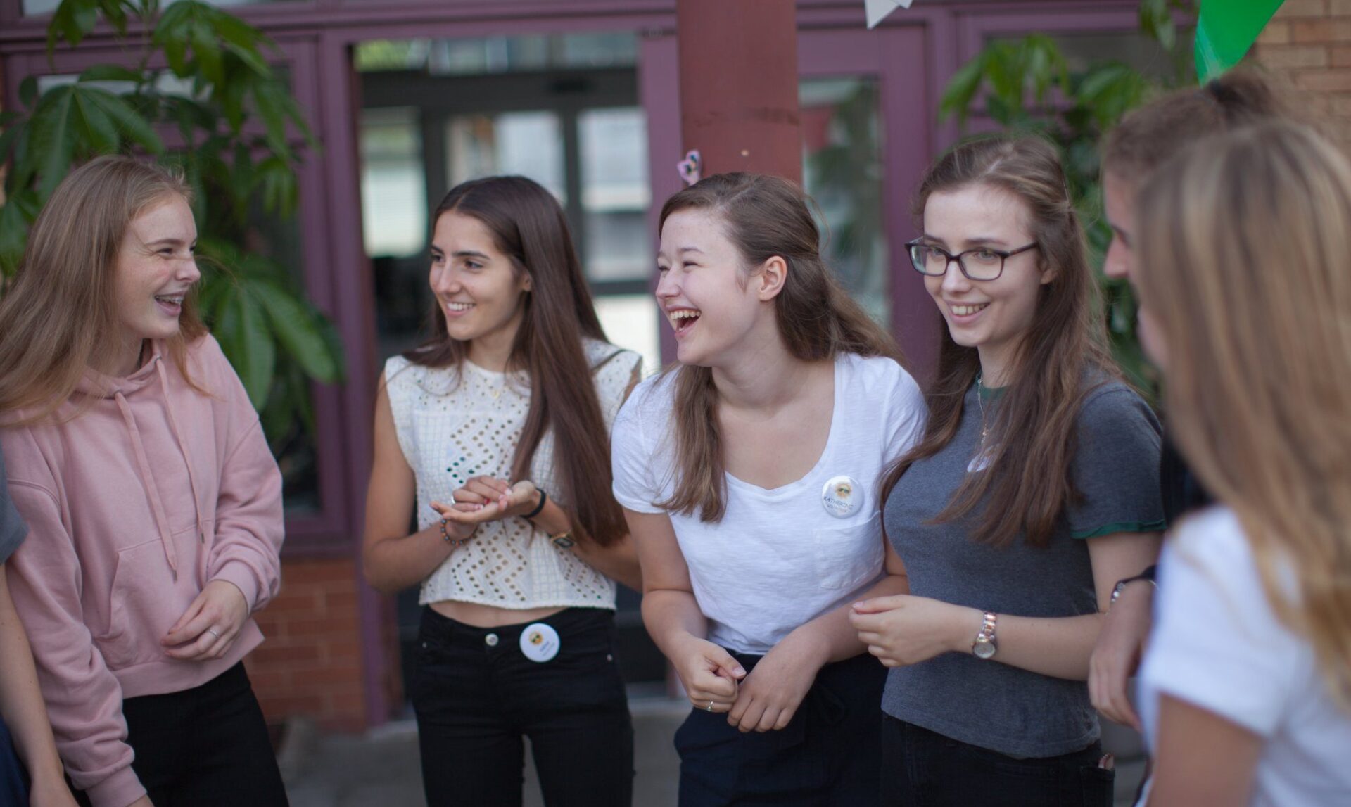 Group of young female volunteers laughing outside of Revitalise centre