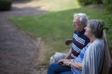 Elderly couple sitting on a bench outside Revitalise Netley Waterside House
