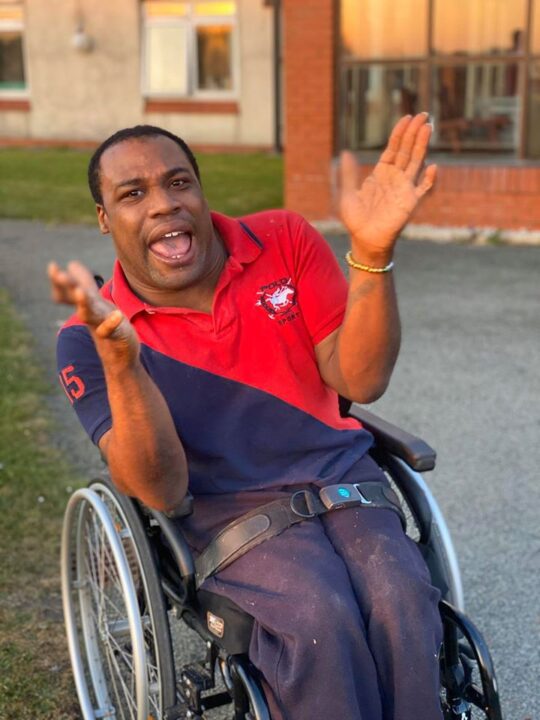 Revitalise guest in wheelchair clapping and smiling