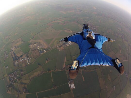 Person skydiving with view looking down over green fields
