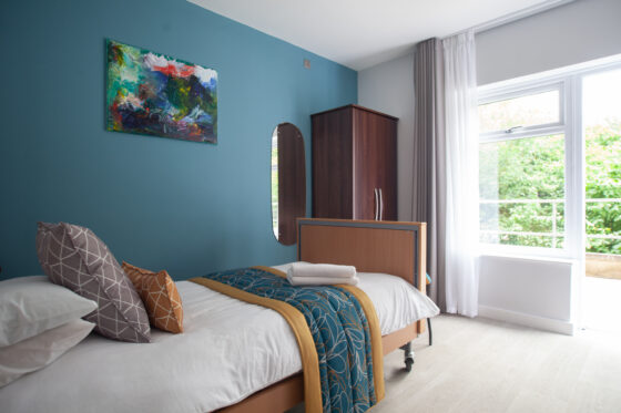 Refurbished bedroom in Revitalise Jubilee Lodge featuring teal and gold soft furnishing accents and fully accessible furniture