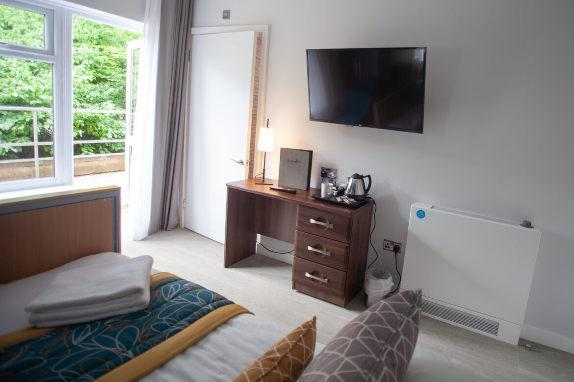 Bedroom at Jubilee Lodge showing room details including bed with soft furnishings, television and desk