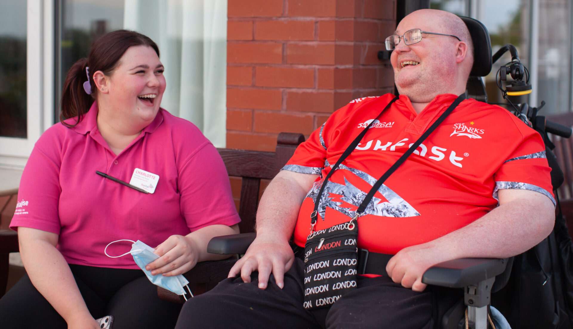 Female Revitalise team member laughing with a male guest in a wheelchair