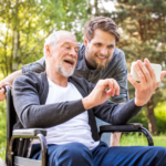 An elderly man and a younger man enjoying content over a smartphone