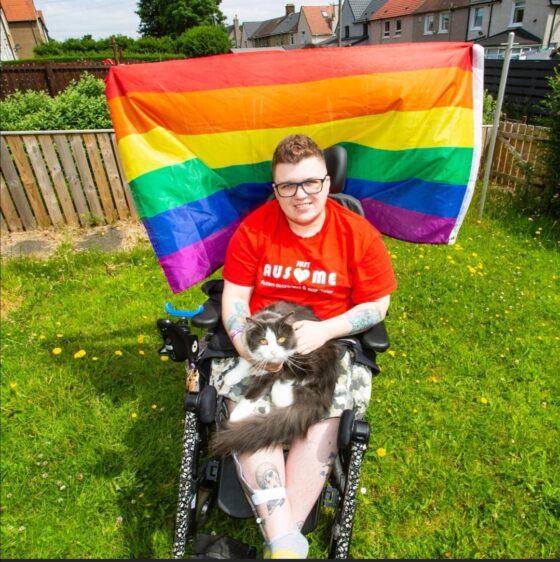 Revitalise guest Luke Murphy with pet cat and Pride flag in the background