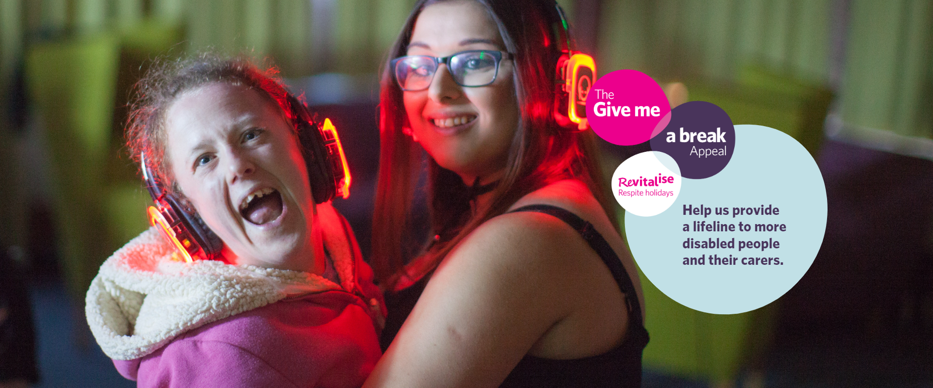 A disabled young woman dancing with an able-bodied young woman at a silent disco, both wearing headphones