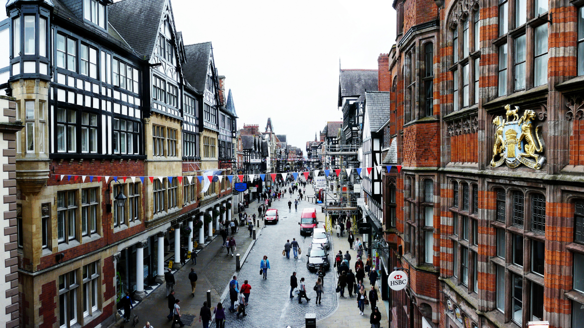 An image of the cultural high street of Chester City. City's iconic black-and-white architecture can be seen on the buildings on the left and right side of the street.