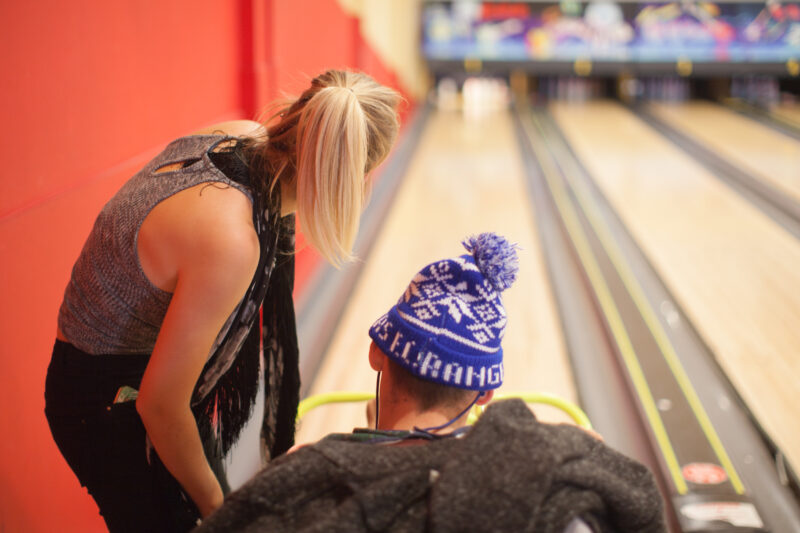 Man in wheelchair being assisted at bowling