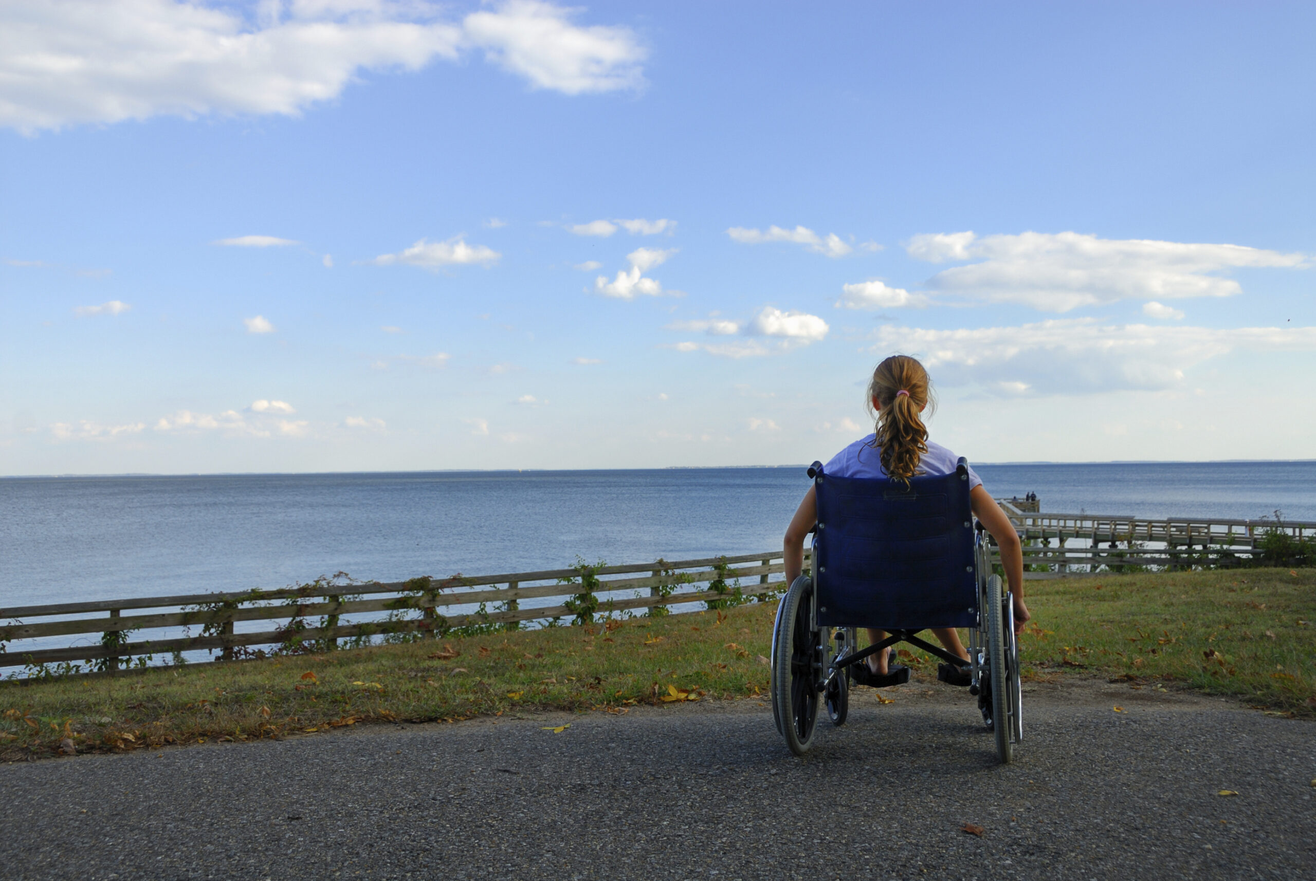 Younger disabled woman in a wheelchair looking out to sea