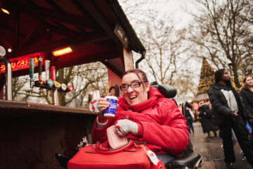 A guest from Revitalise Jubilee Lodge is drinking a cup of hot mulled wine while enjoying their day at the Hyde Park Winter Wonderland