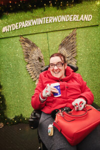 A guest from Revitalise Jubilee Lodge is drinking a cup of hot mulled wine while enjoying their day at the Hyde Park Winter Wonderland