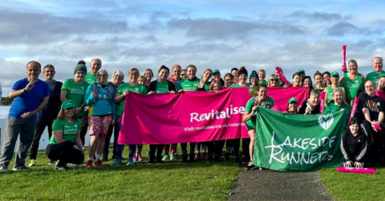 An image of runners from Southport's running club Lakeside Runners posing in front of the Marine Lake near Sandpipers.