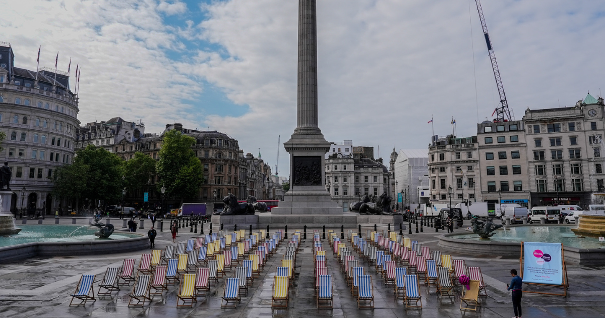 129 deck chairs lined by at Trafalgar Square to signify that only 1 out of 129 unpaid carers is able to get respite support. The Nelson's Column can be seen in the background.